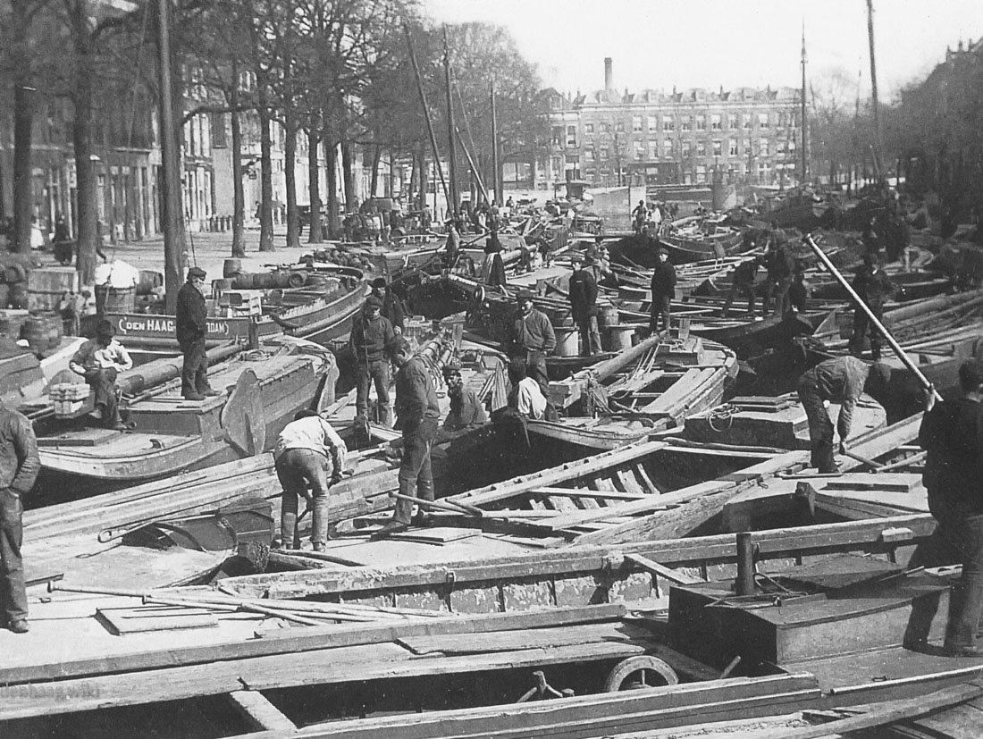Drukte op de Bierkade gracht. Dit zijn Westlandse schippers die hun groenten naar Den Haag getransporteerd hebben. Deze foto werd aan het begin van de twintigste eeuw gemaakt.